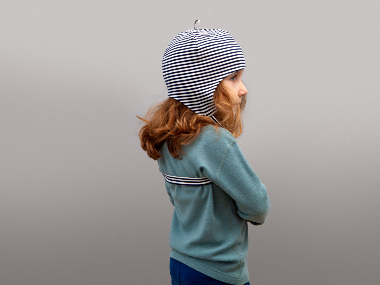 gestreifte Mütze mit Band aufegesetzt auf dem Kopf eines Kindes von schräg hinten